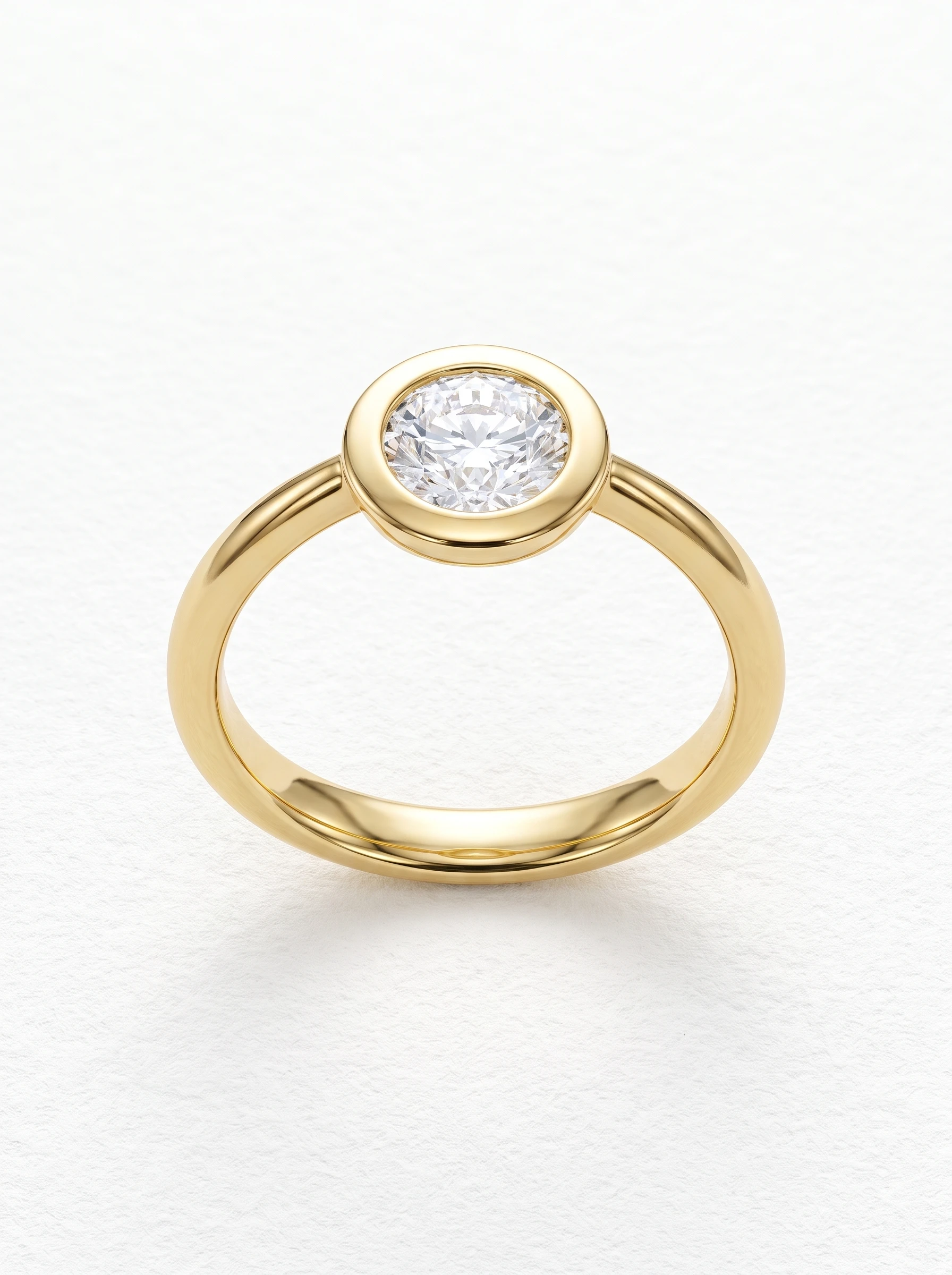 Round brilliant bezel engagement ring in yellow gold standing upright, polished rim and plain rounded band