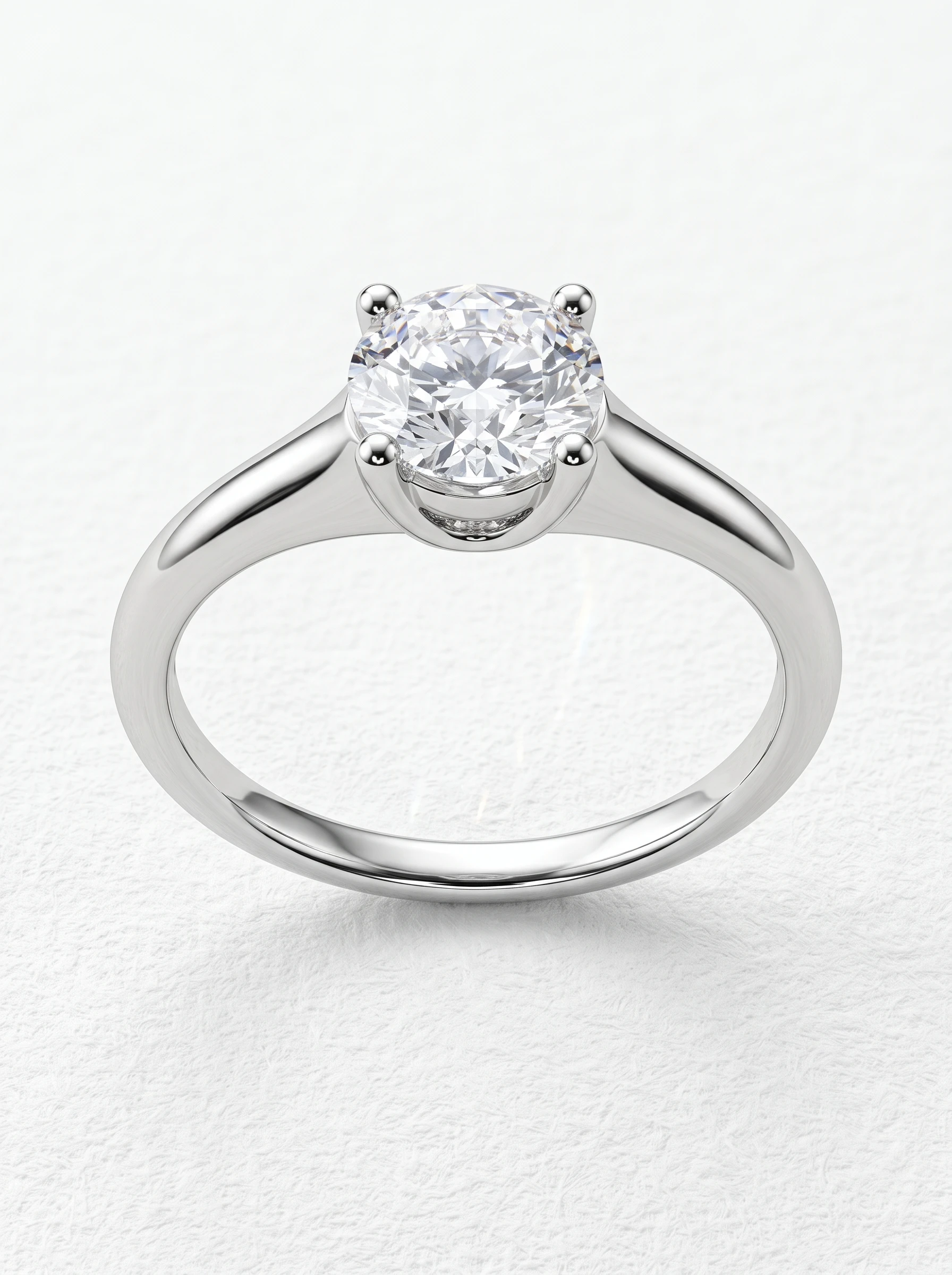 Round brilliant solitaire engagement ring in white gold, front view of four rounded prongs and tapered cathedral shoulders