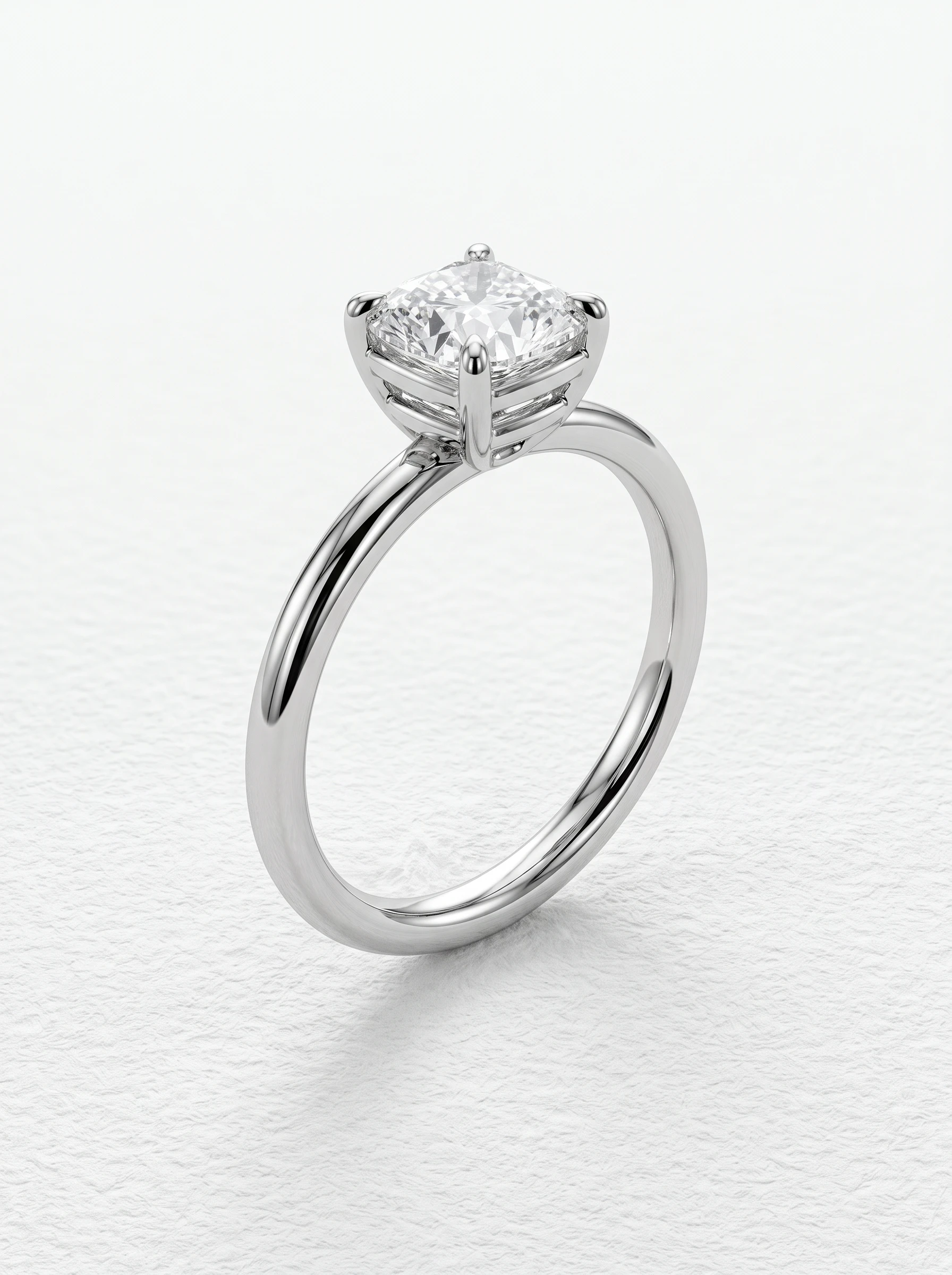 Cushion cut solitaire engagement ring in platinum standing upright, four claw prongs and double-rail basket head