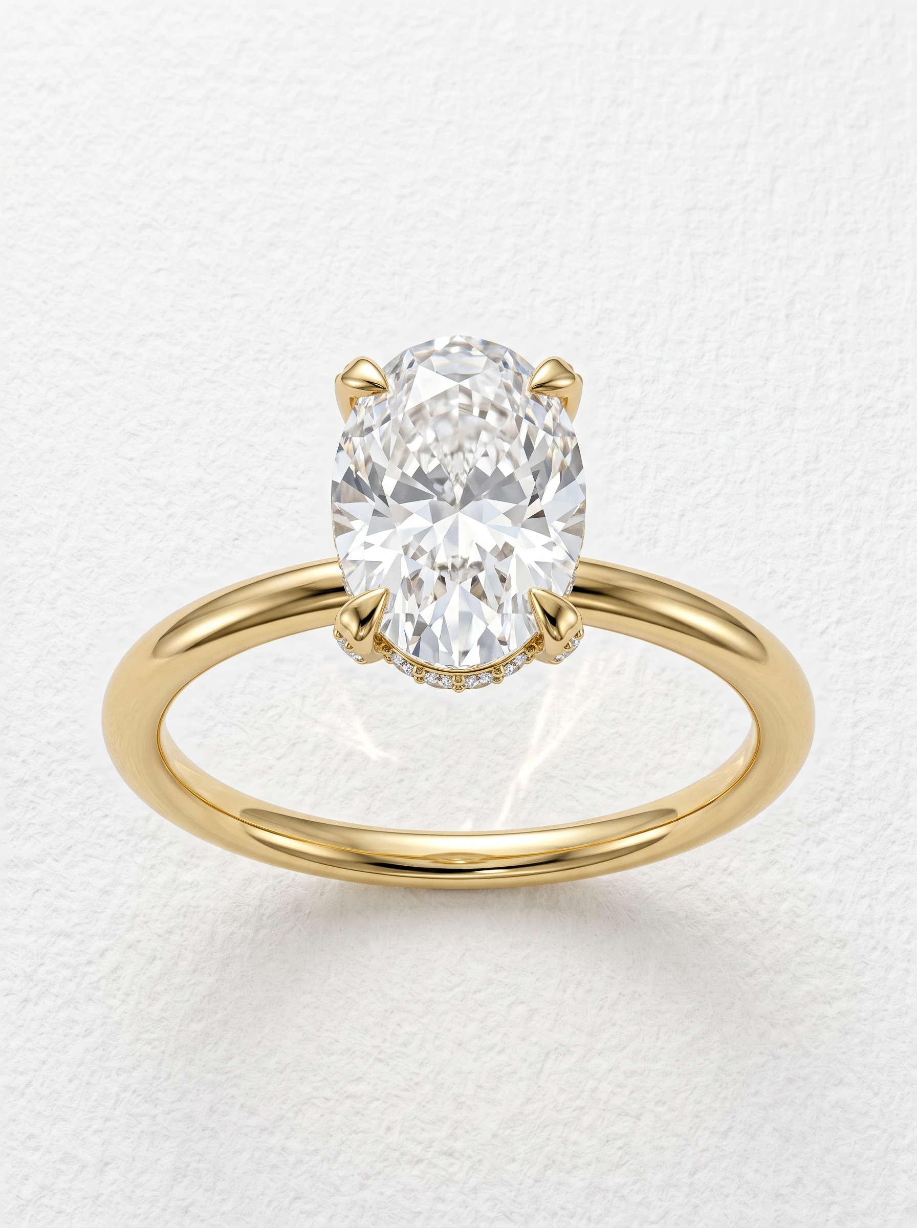 Oval hidden halo pave engagement ring in yellow gold, face-up view of the oval center in four claw prongs