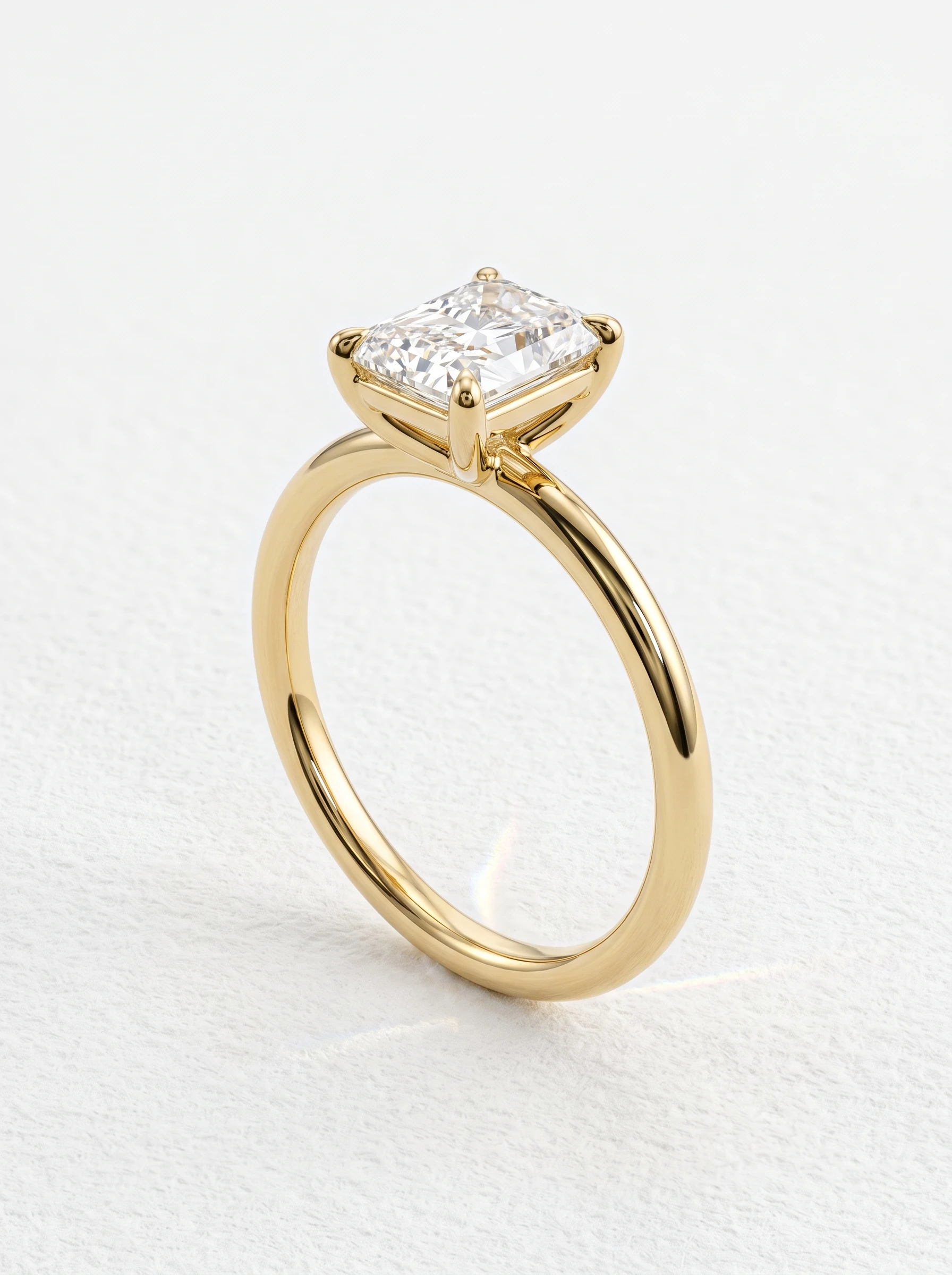Radiant cut solitaire engagement ring in yellow gold standing upright, four claw prongs and single-rail basket