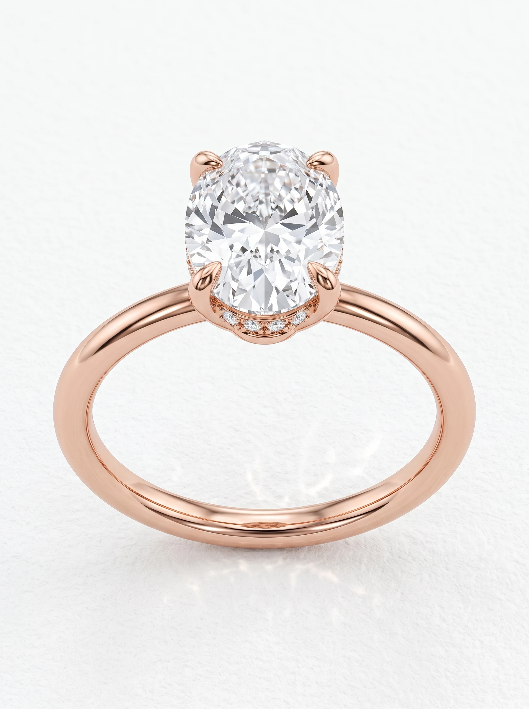 Oval hidden halo solitaire engagement ring in rose gold, front view with four claw prongs and a slim round band