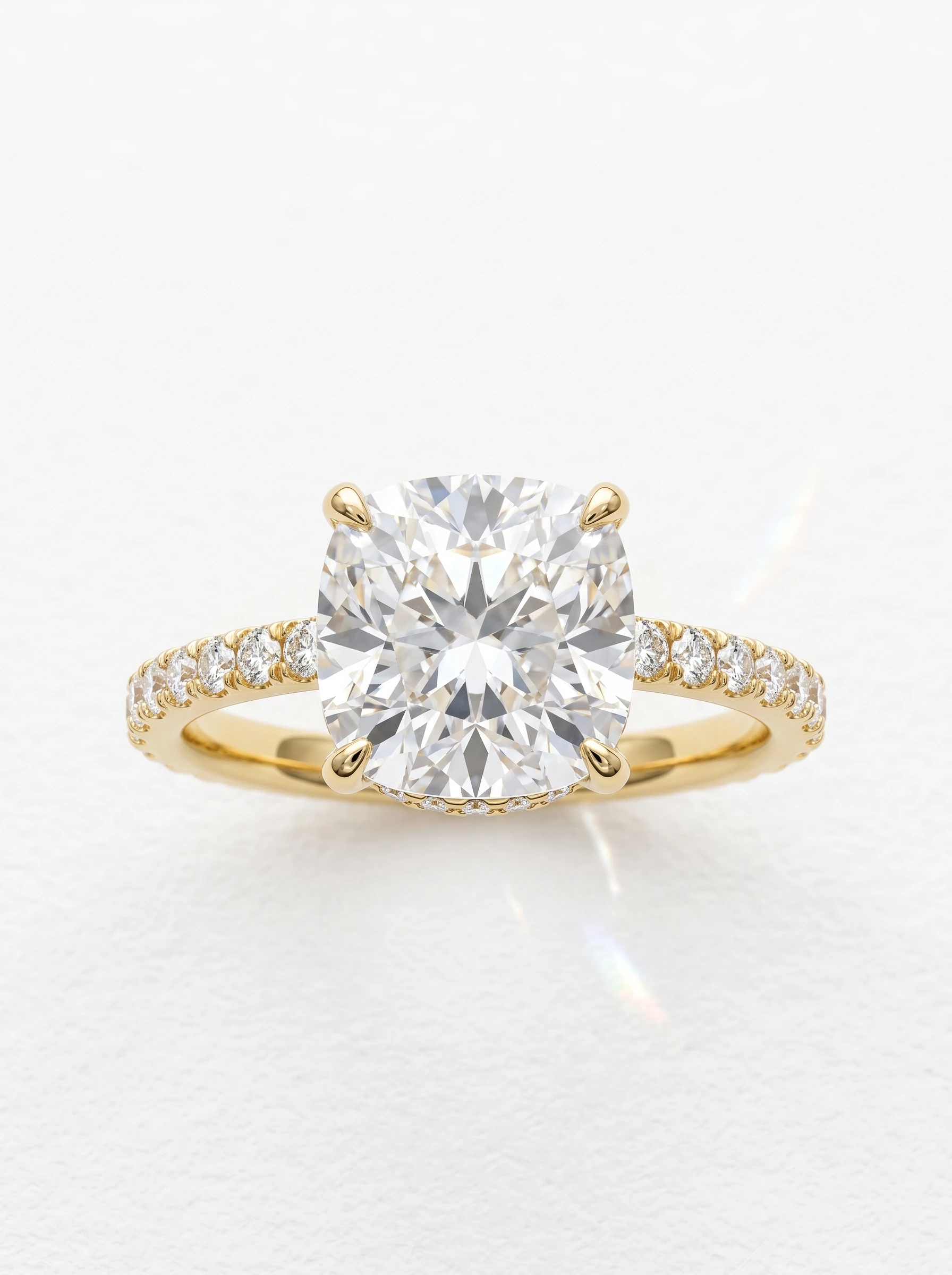 Cushion cut hidden halo pave engagement ring in yellow gold, pictured upright with pave diamonds along the shank
