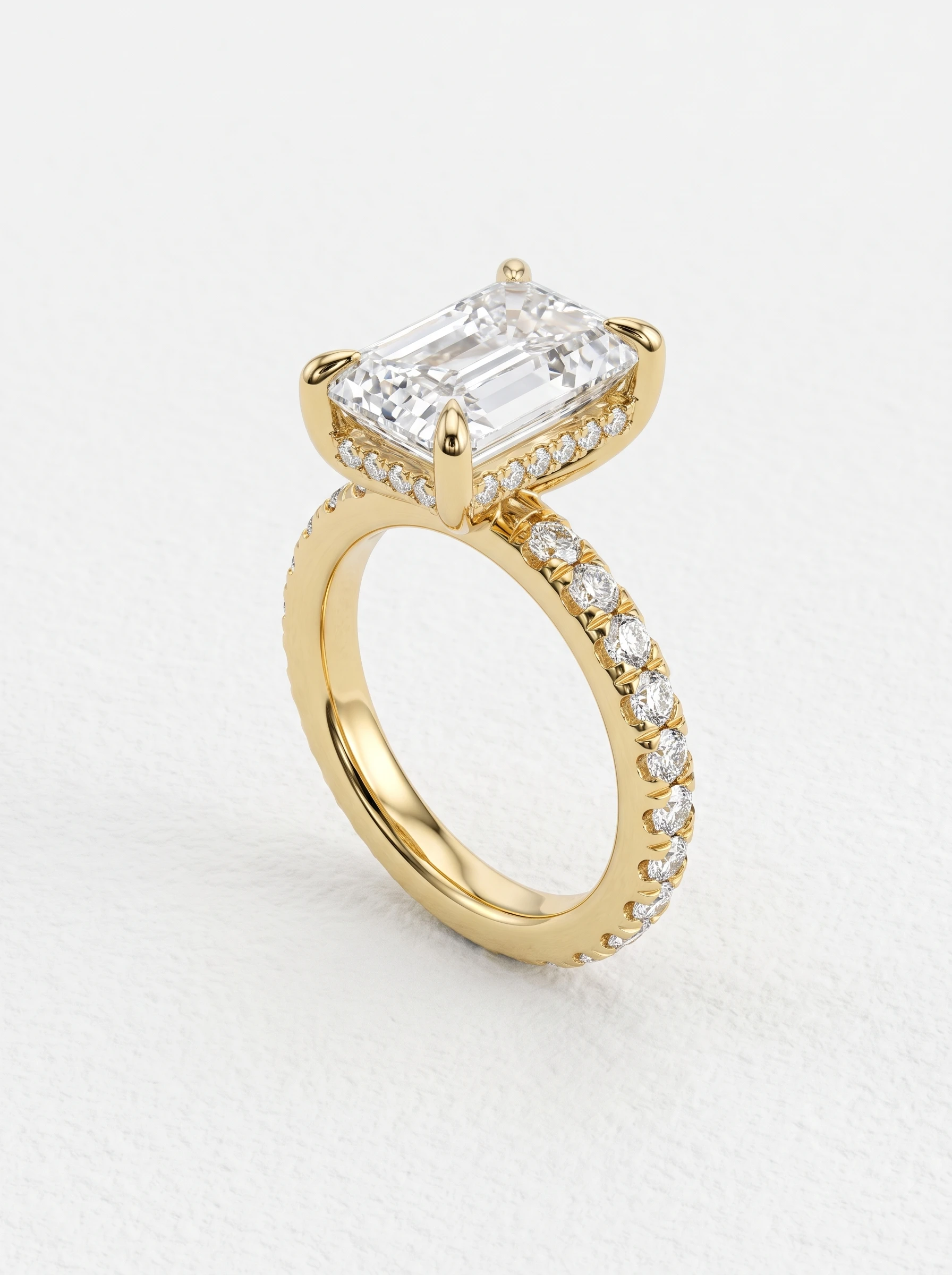 Radiant cut hidden halo pave engagement ring in yellow gold standing upright, four claw prongs and pavé band