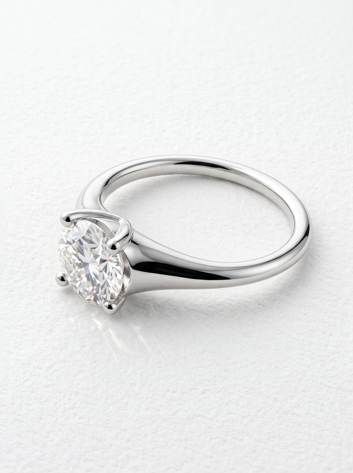 Bague de fiançailles solitaire ronde en or blanc couchée sur le côté, chaton surélevé et anneau fin poli