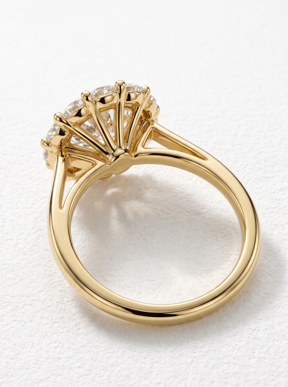 Dessous d'une bague de fiançailles halo en or jaune, tiges d'or déployées comme un bouquet