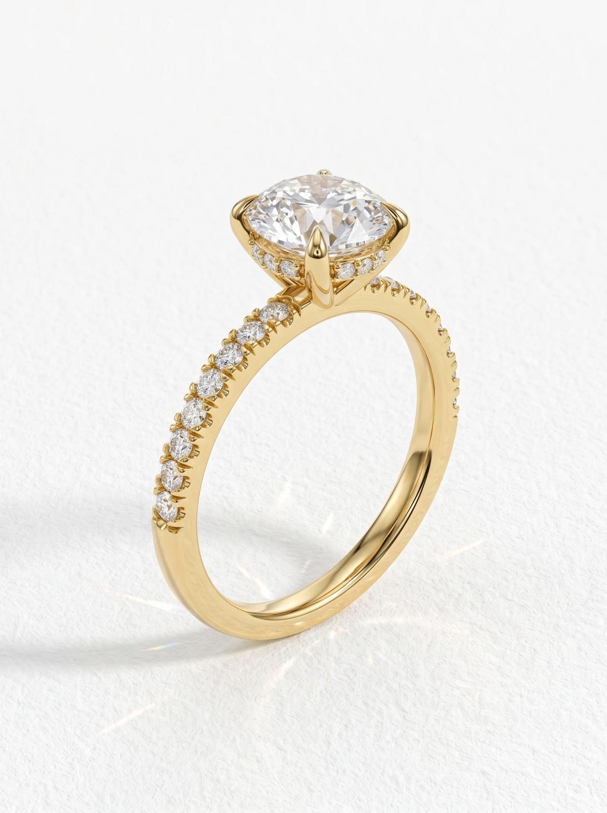 Vue de côté d'une bague à halo caché en or jaune montrant le chaton à griffes et l'anneau pavé