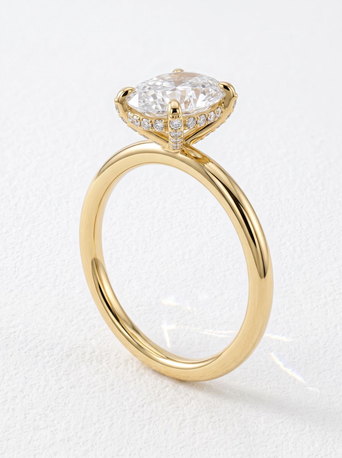Bague ovale en or jaune posée droite, griffes bordées de pavé et halo caché vus de profil