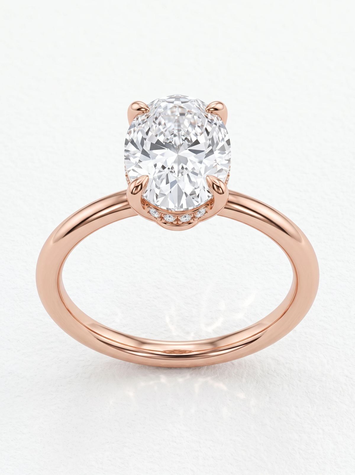 Bague de fiançailles solitaire ovale halo caché en or rose vue de face, quatre griffes et anneau fin
