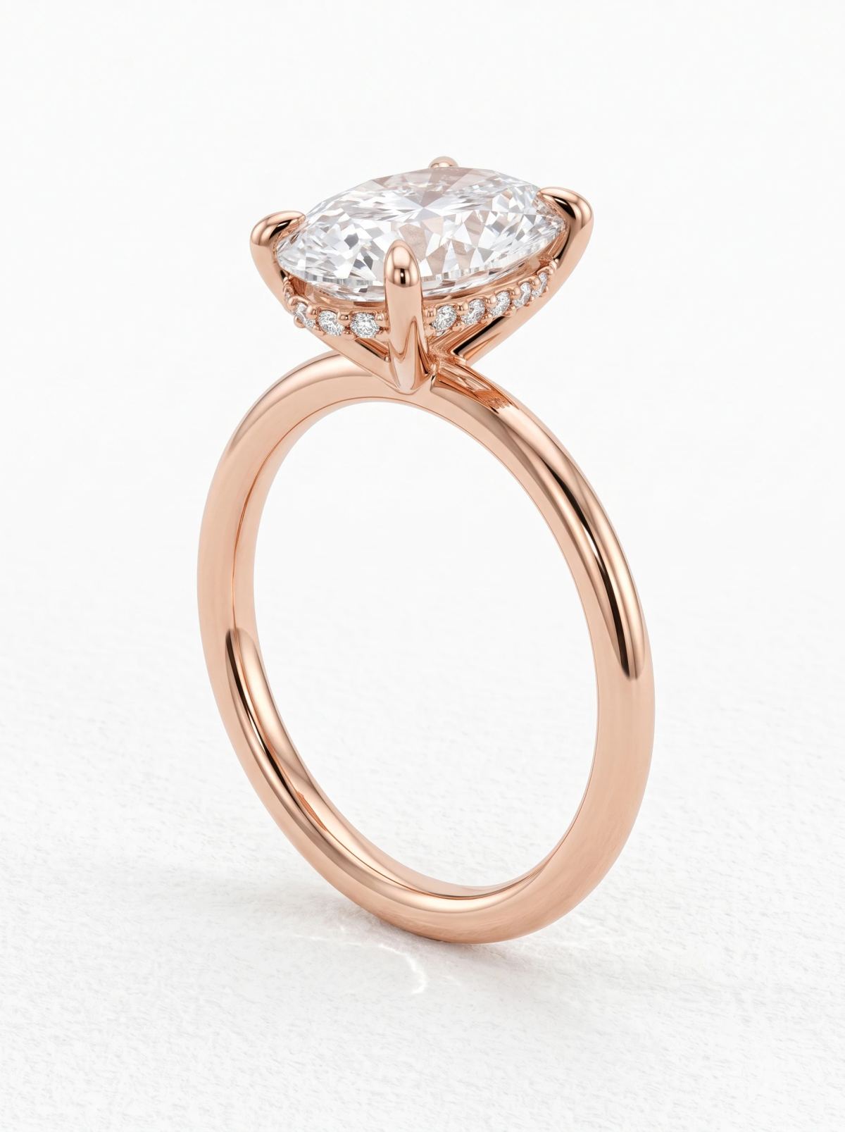 Bague ovale en or rose debout vue de trois quarts, montrant le halo caché de petits diamants sous la pierre