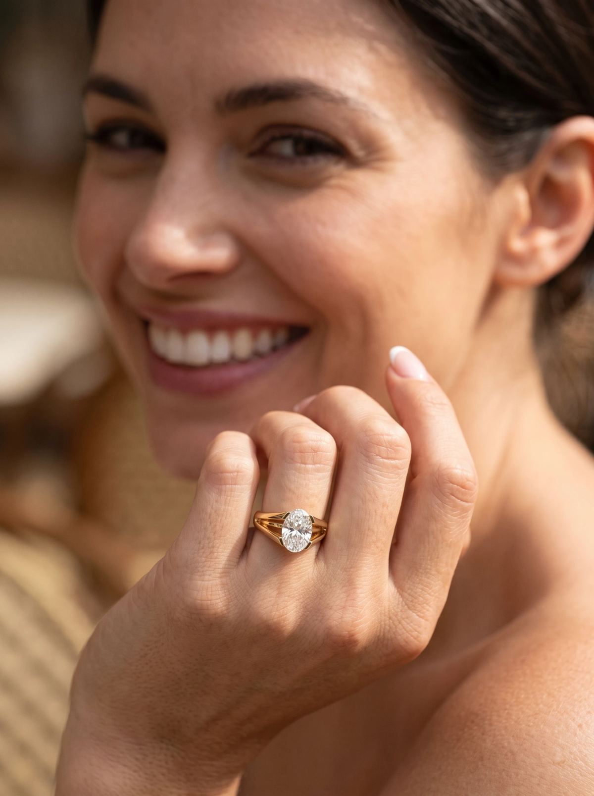 Bague de fiançailles ovale à anneau divisé en or jaune portée à la main près du visage souriant