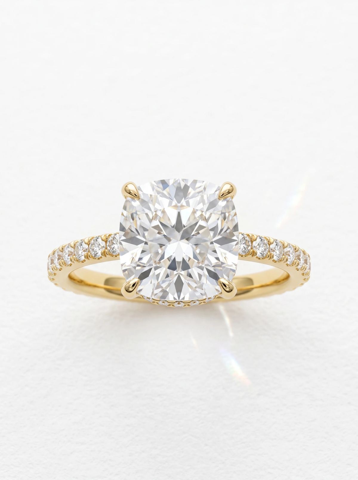 Bague de fiançailles coussin halo caché pavé en or jaune, posée droite sur l'anneau