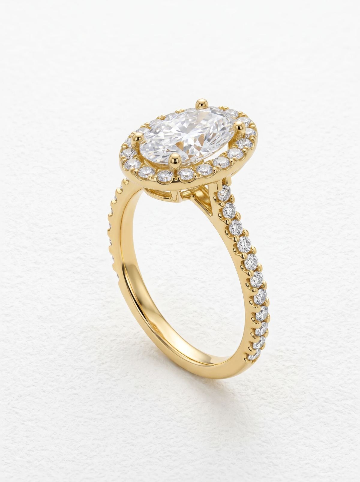 Bague halo en or jaune vue de trois quarts, pierres pavées le long de l'anneau et de la galerie
