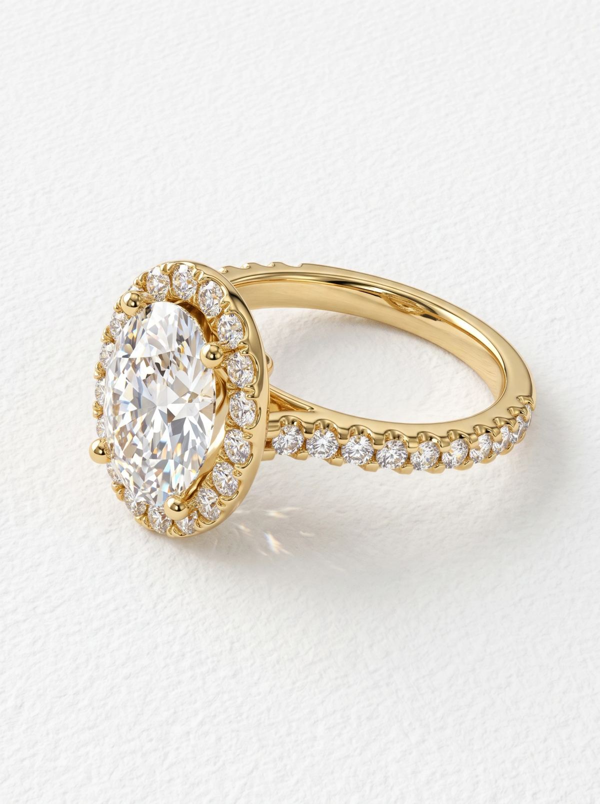 Vue de profil d'une bague halo en or jaune, épaules cathédrale et anneau pavé