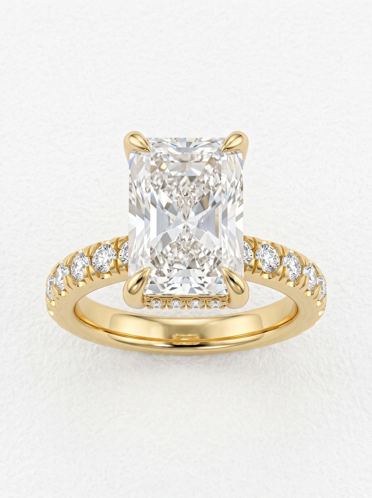 Vue de face d'une bague diamant taille radiant allongée en or jaune, griffes effilées et épaules pavées