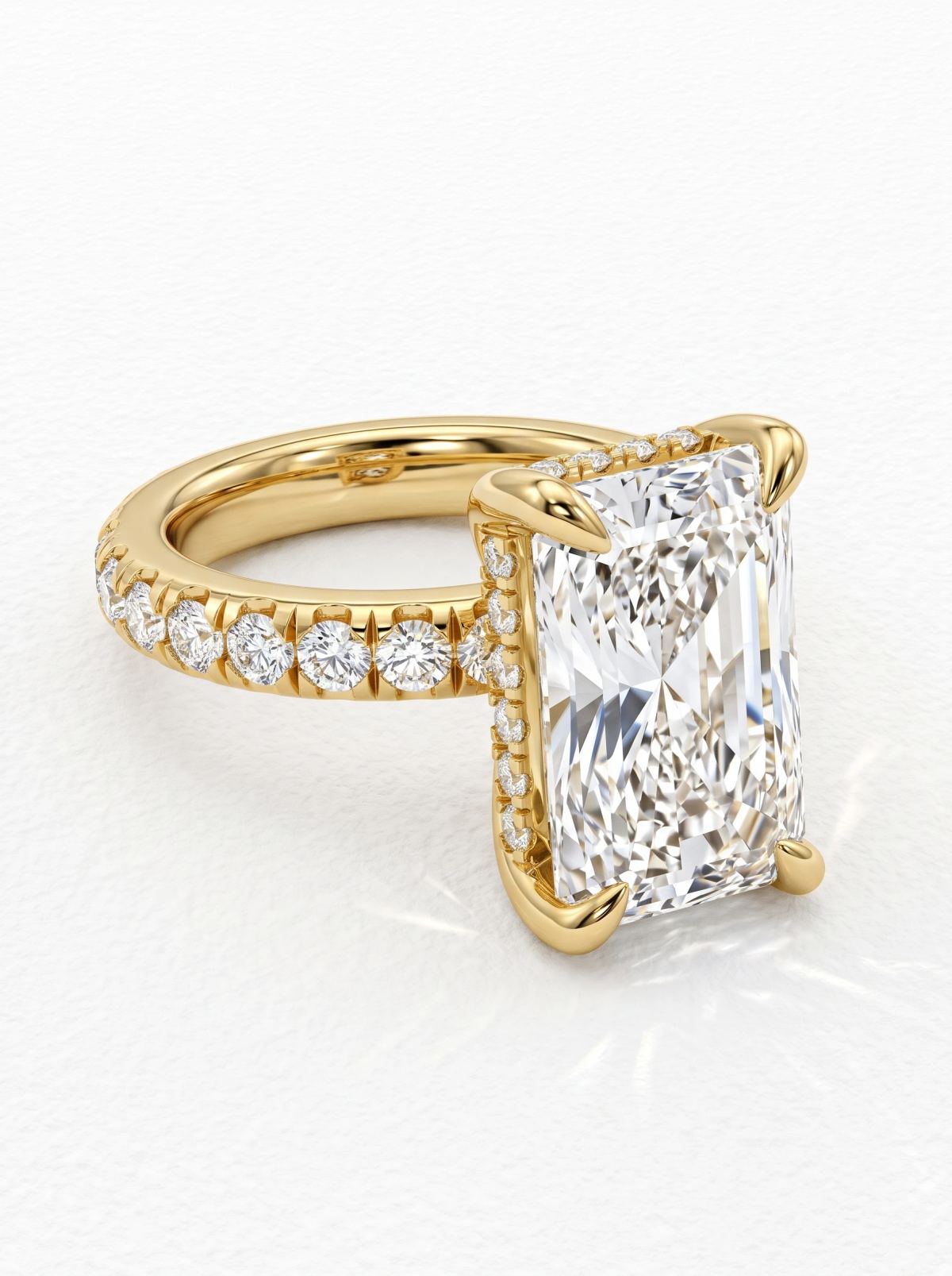 Bague de fiançailles radiant en or jaune couchée sur le côté, montrant le halo caché sous la pierre centrale