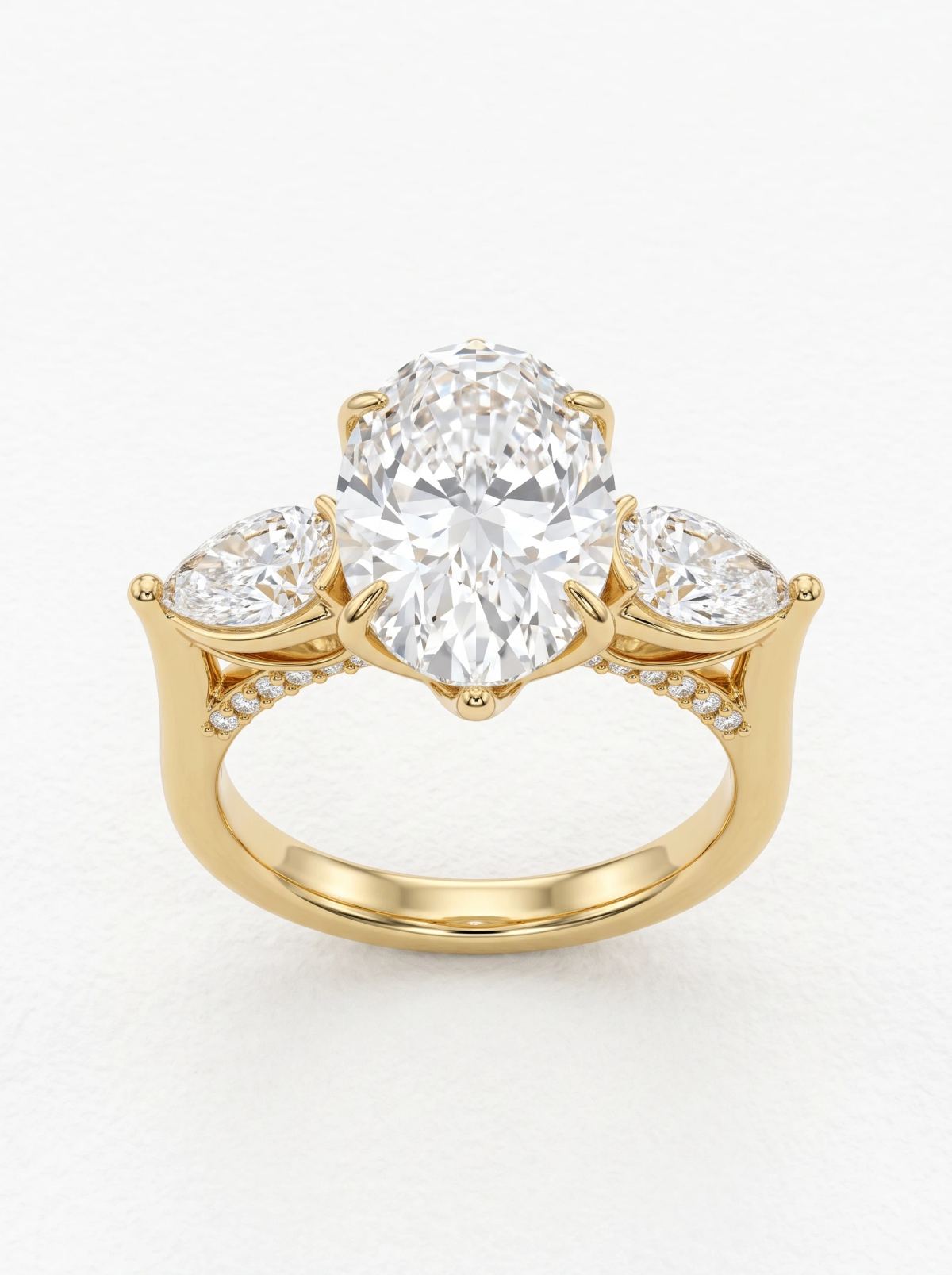 Bague de fiançailles trilogie ovale et poires en or jaune, vue de face avec six griffes et pont pavé