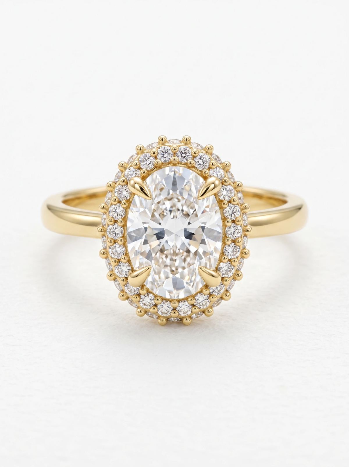 Vue de dessus d'une bague ovale double halo en or jaune, griffes effilées et courtes griffes perlées