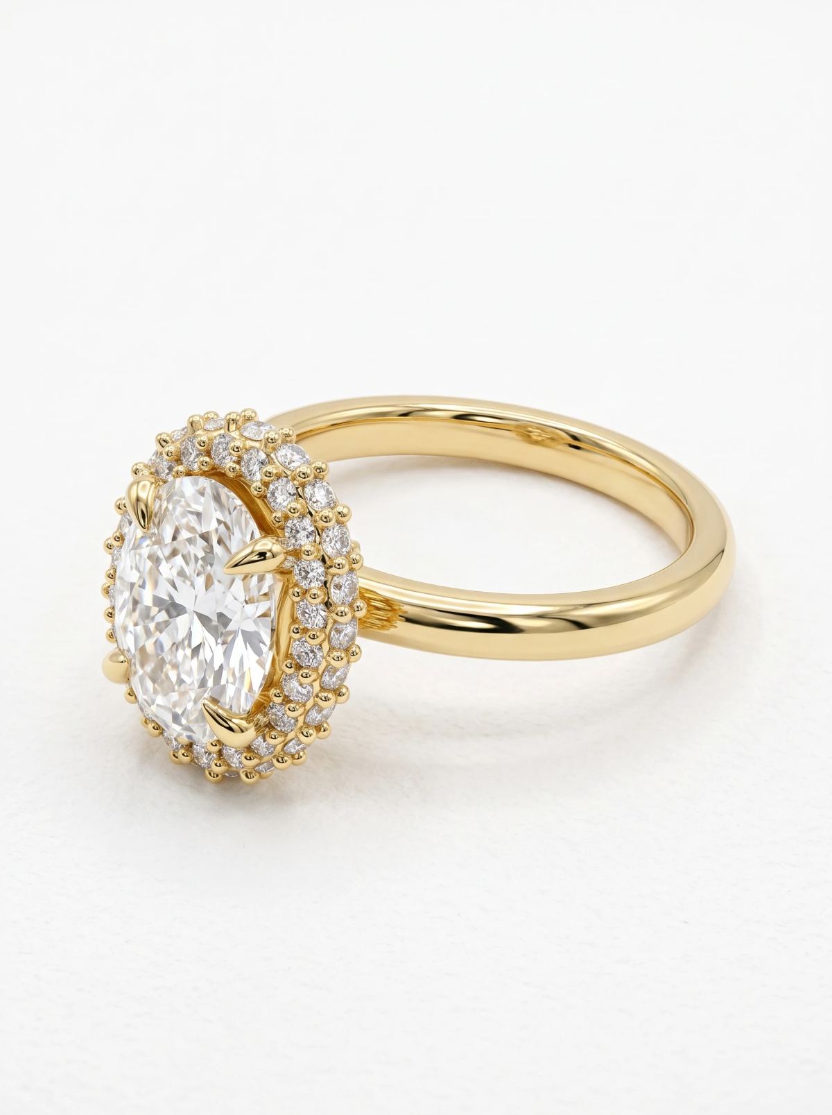 Bague ovale à halo en or jaune vue de côté, deux rangs de diamants sertis grain autour de la pierre centrale